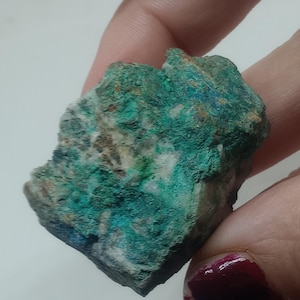 May include: A rough, irregularly shaped rock with a green, blue, and white mineral formation. The rock has a rough, textured surface.