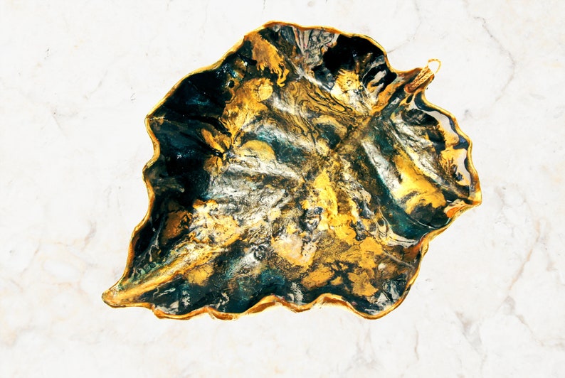 One more angle of a black and gold leaf-shaped decorative paper clay bowl-ornament with wavy edge and glossy finish. Suitable for holding keys, jewelry and other trinkets. Can be used as table, shelf décor.