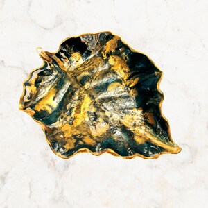 Another angle of a black and gold leaf-shaped decorative paper clay bowl-ornament with wavy edge and glossy finish. Suitable for holding keys, jewelry and other trinkets.