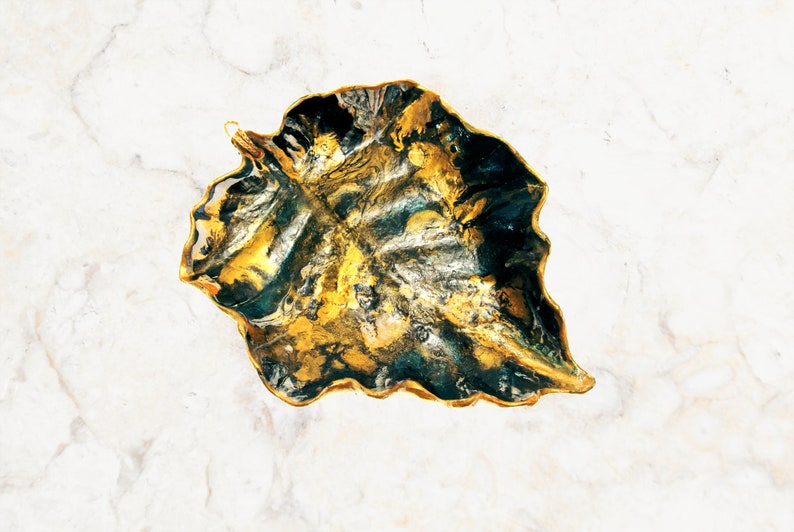 Another angle of a black and gold leaf-shaped decorative paper clay bowl-ornament with wavy edge and glossy finish. Suitable for holding keys, jewelry and other trinkets.
