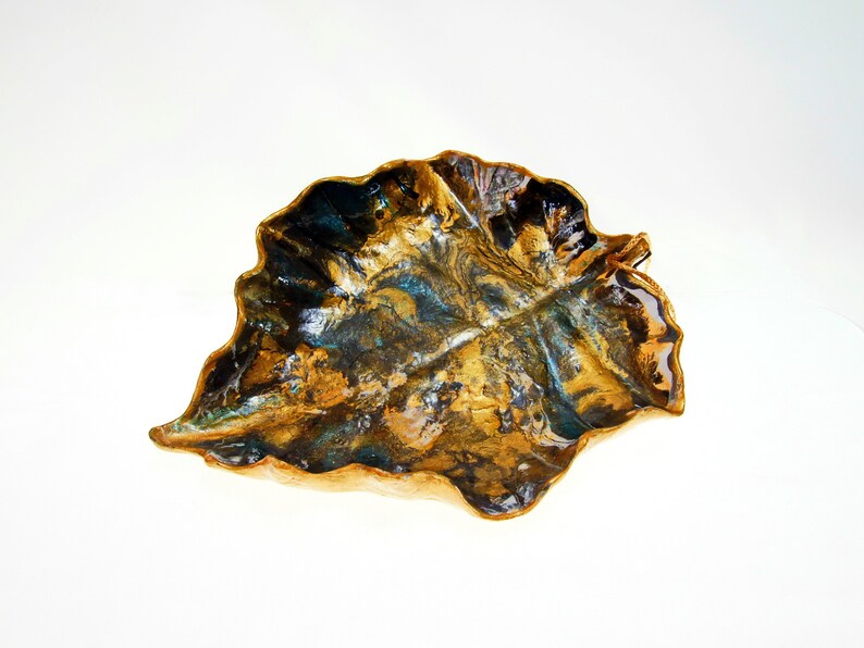 A black and gold leaf-shaped decorative paper clay bowl-ornament with wavy edge and glossy finish. Suitable for holding keys, jewelry and other trinkets.
