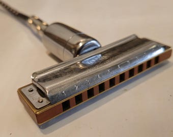 May include: A silver harmonica with a brown wooden mouthpiece and a silver metal attachment. The harmonica has numbers 1 through 7 printed on the top.