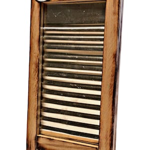 May include: A wooden washboard with a metal washboard surface. The washboard has a handle and three decorative metal buttons on the top. The buttons have a smiley face, a blue flower, and a blue star design. The washboard is labelled "Washboard Blues Mattacchi's Made in Italy."
