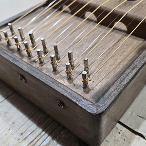 May include: A wooden musical instrument with strings and tuning pegs. The instrument has a dark brown finish and is made of wood.