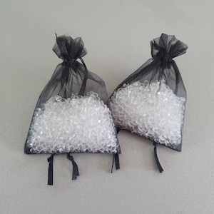 May include: Two black mesh bags filled with clear silica gel beads. The bags have black drawstrings.