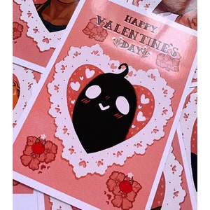Puede incluir: Tarjeta de felicitaci&oacute;n del D&iacute;a de San Valent&iacute;n con fondo rosa y un personaje de dibujos animados negro dentro de un marco en forma de coraz&oacute;n. La tarjeta presenta el texto "Happy Valentine's Day" en una fuente decorativa, con motivos florales y de coraz&oacute;n.