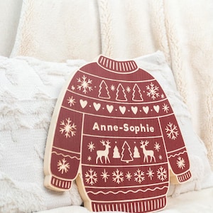 Peut inclure: Décoration de Noël en bois en forme de pull, de couleur bordeaux avec un bord en bois clair. Le motif du pull comprend des flocons de neige, des arbres, des cœurs et des rennes. Le nom "Anne-Sophie" est imprimé.
