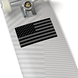 May include: A black and white American flag sticker on a gray and white striped skateboard deck.
