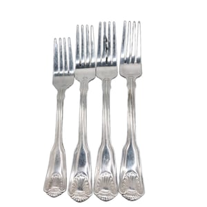 May include: A set of four silver-toned metal forks arranged side by side. Each fork features a four-tine head and a long, slender handle that terminates in a decorative, embossed shell motif at the base. The metal has a polished, reflective finish.