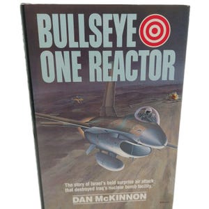 May include: A book cover with the title "BULLSEYE ONE REACTOR" in large, light blue letters. The cover features an illustration of a fighter jet in flight over a desert landscape. The text below reads: "The story of Israel's bold surprise air attack that destroyed Iraq's nuclear bomb facility."