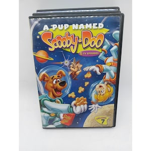 Könnte beinhalten: Eine DVD-Hülle für A Pup Named Scooby-Doo Volume 7 mit fünf TV-Episoden. Das Cover zeigt Scooby-Doo und Shaggy in Raumanzügen, die neben einem Planeten und dem Mond schweben, mit schwebenden Snacks und dem Text A Pup Named Scooby-Doo.