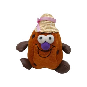 May include: A brown plush toy shaped like a potato with a smiling face, large white eyes, and a purple nose. It wears a small straw hat adorned with a light pink ribbon. The toy has dark brown arms and feet attached to its soft, textured body.