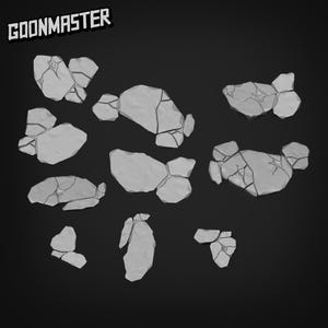 May include: A collection of gray, irregularly shaped stone fragments with cracked surfaces, scattered against a dark background. The text "GOONMASTER" is in the upper left corner. These pieces appear to be for a tabletop game.
