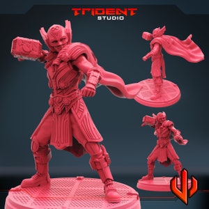 May include: A red plastic miniature figurine of a warrior wearing a helmet and armor, holding a hammer in one hand and a cape flowing behind them. The figurine is standing on a round base.