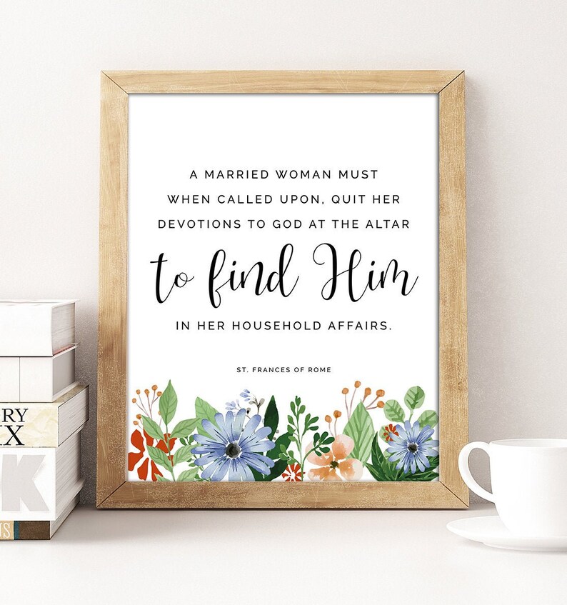 May include: A printable quote about a married woman's duties to God and her household. The quote is framed in a light wood frame and surrounded by a floral border. The text reads: "A married woman must when called upon, quit her devotions to God at the altar to find Him in her household affairs. - St. Frances of Rome"