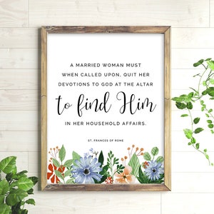 May include: A framed print with a white background and black text that reads "A married woman must when called upon, quit her devotions to God at the altar to find Him in her household affairs. St. Frances of Rome". The print is decorated with a floral border of red, orange, blue, and green flowers.