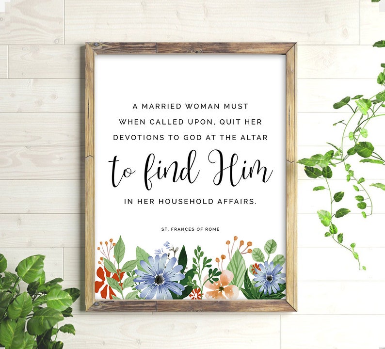 May include: A framed print with a white background and black text that reads "A married woman must when called upon, quit her devotions to God at the altar to find Him in her household affairs. St. Frances of Rome". The print is decorated with a floral border of red, orange, blue, and green flowers.