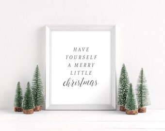 Peut inclure: Impression encadrée blanche avec le texte "HAVE YOURSELF A MERRY LITTLE CHRISTMAS" en écriture cursive noire. L'impression est entourée de quatre petits sapins artificiels.