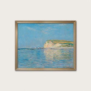 May include: A framed landscape painting depicts a coastal scene with a light blue sky and ocean. The artwork features a cliffside with green and yellow vegetation, a sandy beach, and figures. The painting is in a gold frame.