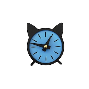 May include: A black and blue cat-shaped alarm clock. The clock face is light blue with black hands and hour markers. The clock has a black frame and cat ear-shaped top. The clock is a decorative item.