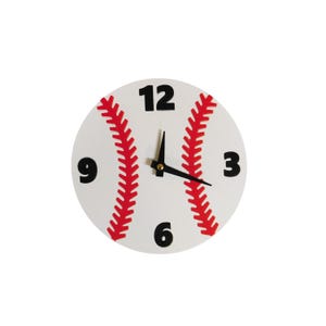 May include: A round baseball-themed clock with a white face and red stitching details. The clock features black numbers at the 12, 3, 6, and 9 o'clock positions, with black clock hands.