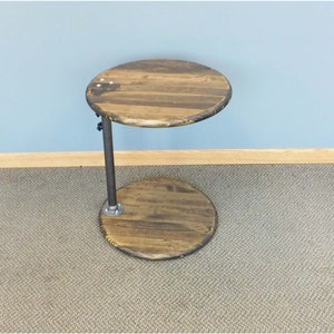 May include: A round wooden side table with a metal base. The table has a dark brown stain and a natural wood grain. The base is made of black metal pipe.
