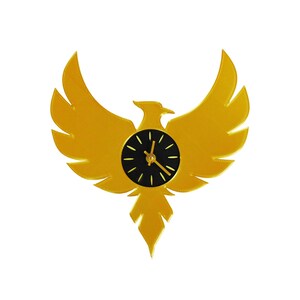 May include: A golden-yellow wall clock in the shape of a phoenix with outstretched wings. The clock face is black with gold hands and hour markers. The clock is a decorative item.