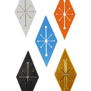K&ouml;nnte beinhalten: F&uuml;nf rautenf&ouml;rmige Ornamente in Wei&szlig;, Blau, Orange, Schwarz und Gold. Jedes hat ein Sternmuster in der Mitte. Die Ornamente sind wahrscheinlich f&uuml;r Dekorationen oder Bastelarbeiten gedacht.