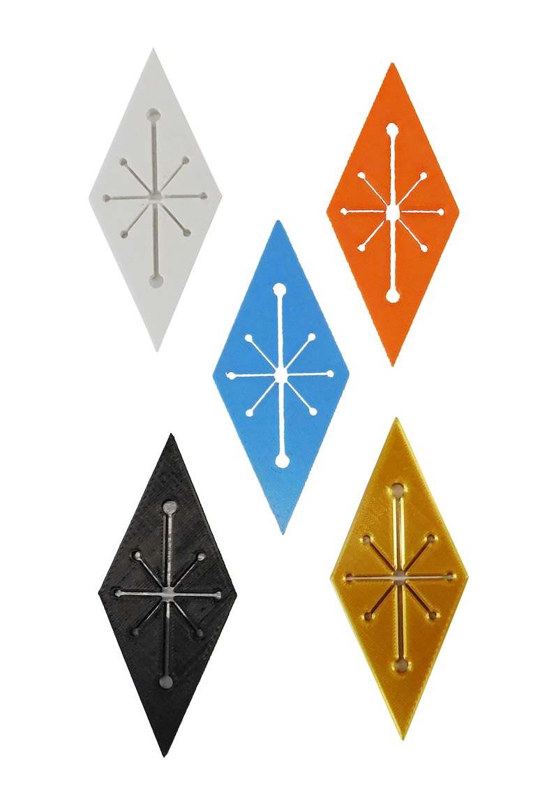 K&ouml;nnte beinhalten: F&uuml;nf rautenf&ouml;rmige Ornamente in Wei&szlig;, Blau, Orange, Schwarz und Gold. Jedes hat ein Sternmuster in der Mitte. Die Ornamente sind wahrscheinlich f&uuml;r Dekorationen oder Bastelarbeiten gedacht.
