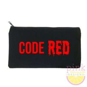 May include: Black zippered pouch with the words "CODE RED" in dripping red letters. The pouch has a rectangular shape and a zipper closure. The lower right corner features a pink and yellow logo that says "pink lemonade designs."
