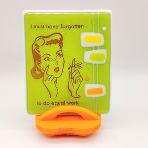 May include: A green glass tile with a retro illustration of a woman with the text "I must have forgotten to do equal work."
