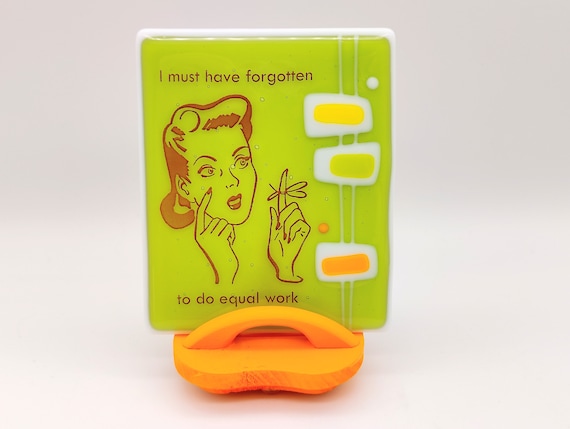 Atomic-age feminist graphic art on glass with a custom stand — mid-century retro meets modern wit, and genuinely looks like nothing else on the market.