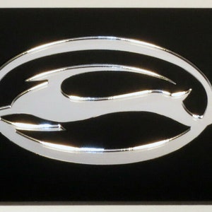 May include: Black license plate with a silver Chevrolet bowtie logo. The logo is a stylized silhouette of a bowtie with a silver finish.