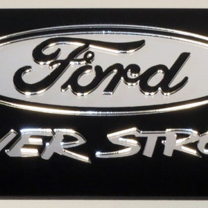 May include: Black metal license plate frame with a silver Ford logo and the words "POWER STROKE" in silver lettering.