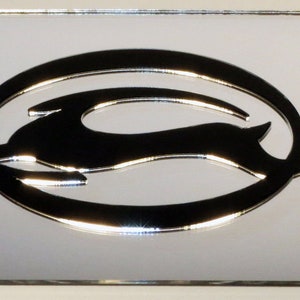 May include: A silver chrome license plate frame with a raised, black Chevrolet bowtie logo. The logo features a stylized running animal in a circle.