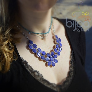 May include: A silver necklace with a large pendant made of blue gemstone cabochons. The pendant is shaped like a flower with a central stone and surrounding stones.