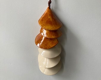 May include: A hanging ceramic mobile with five tiers. The top three tiers are a warm brown color and the bottom two tiers are a creamy white color.