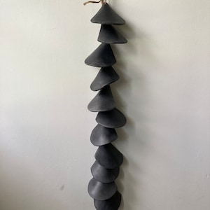 Peut inclure: Un carillon en c&eacute;ramique noire avec une s&eacute;rie de cloches coniques suspendues &agrave; une ficelle.
