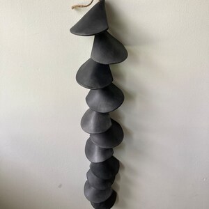 Peut inclure: Un mobile en c&eacute;ramique noire avec une s&eacute;rie de pi&egrave;ces en forme de c&ocirc;ne superpos&eacute;es et en cascade suspendues &agrave; une ficelle de ficelle.