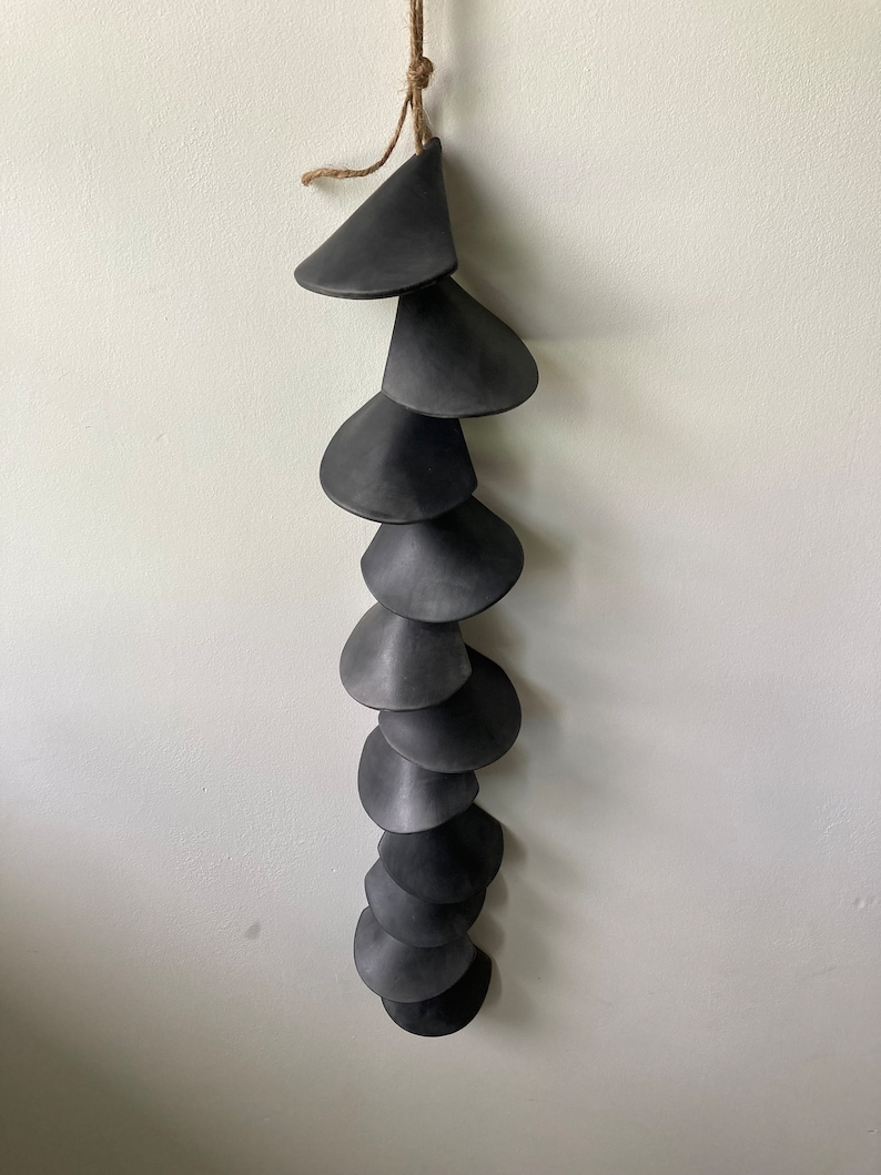 Peut inclure: Un mobile en c&eacute;ramique noire avec une s&eacute;rie de pi&egrave;ces en forme de c&ocirc;ne superpos&eacute;es et en cascade suspendues &agrave; une ficelle de ficelle.