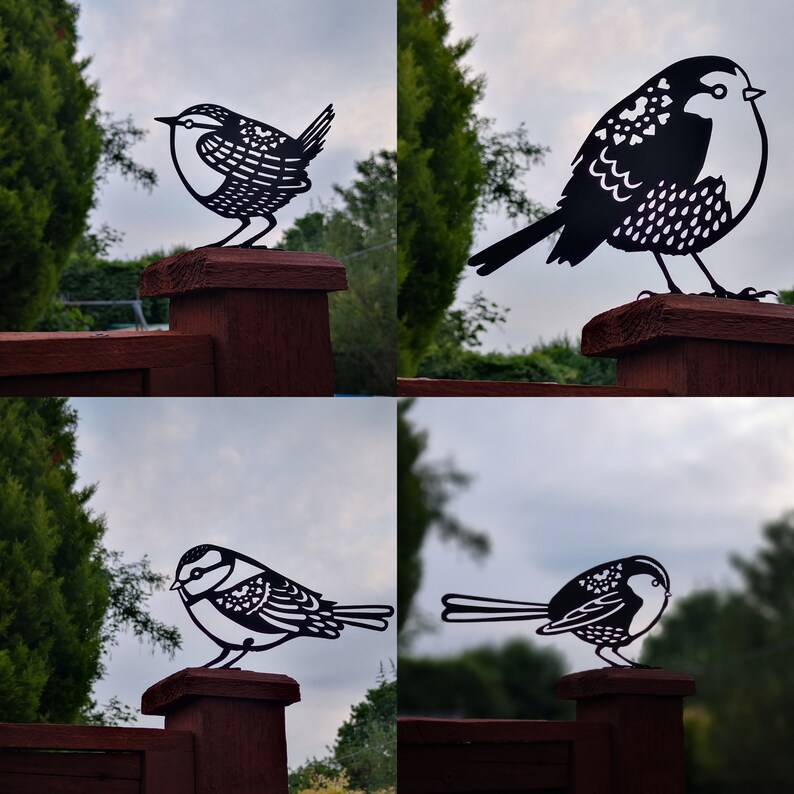 May include: Four black metal bird silhouettes mounted on wooden fence posts. The birds are in different poses, some are perched, some are flying. The birds are all facing the viewer.