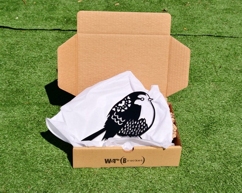 May include: A black metal bird silhouette with a heart pattern, packaged in a brown cardboard box with white tissue paper and the text "War*t(Bracket)".