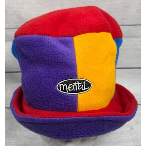 Op de afbeelding: Een kleurrijke fleece hoed met een patchwork ontwerp. De hoed heeft panelen in rood, paars, geel en blauw. Het woord "mental" is op de voorkant geborduurd in een wit ovaal.