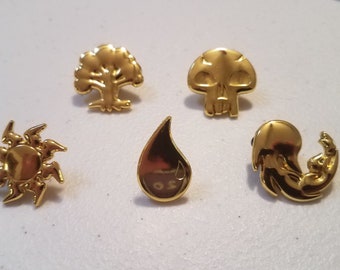 Pins de esmalte dourados com os símbolos de Mana/Terreno de Magic: The Gathering