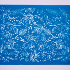 Puede incluir: Un fondo azul con un patrón floral blanco. El patrón incluye hojas, flores y tallos.