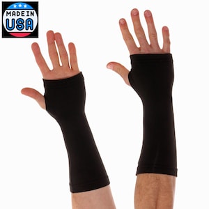 May include: A pair of black arm warmers made of a stretchy fabric. The arm warmers are fingerless and extend to the elbow. The arm warmers are shown on a person's arms with their hands raised.