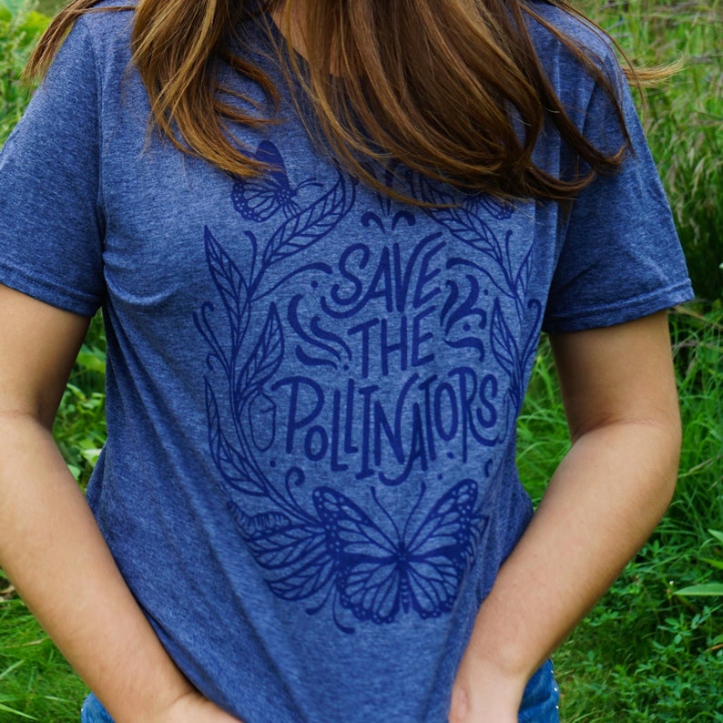 Pu&ograve; includere: Una t-shirt blu melange con un design grafico blu navy che presenta una farfalla e il testo "Save the Pollinators".