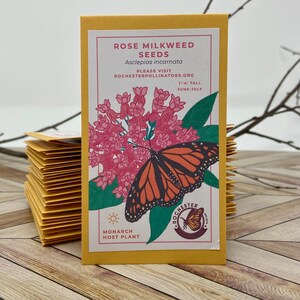 Puede incluir: Un paquete de semillas amarillo con una mariposa monarca y flores rosas. El paquete dice "Rose Milkweed Seeds" y "Asclepias incarnata". Tambi&eacute;n dice "Planta hu&eacute;sped de la monarca" y "Por favor, visite Rochesterpollinators.org".