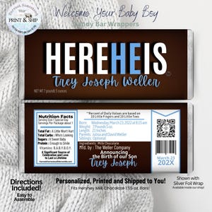 May include: Custom candy bar wrappers for a baby boy, featuring the text "HEREHEIS" and the baby's name. The wrappers include nutrition facts, baby's birth details, and a QR code. The design is brown with blue accents and text.