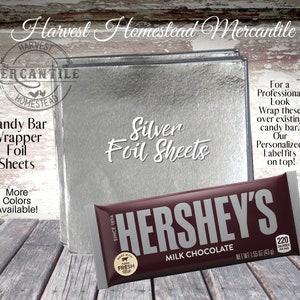 May include: Silver foil sheets for wrapping candy bars. The sheets are shown next to a Hershey's chocolate bar. The text "Silver Foil Sheets" is written in a decorative font. The text "For a Professional Look Wrap these over existing candy bar. Our Personalized Label fits on top!" is also included in the image.